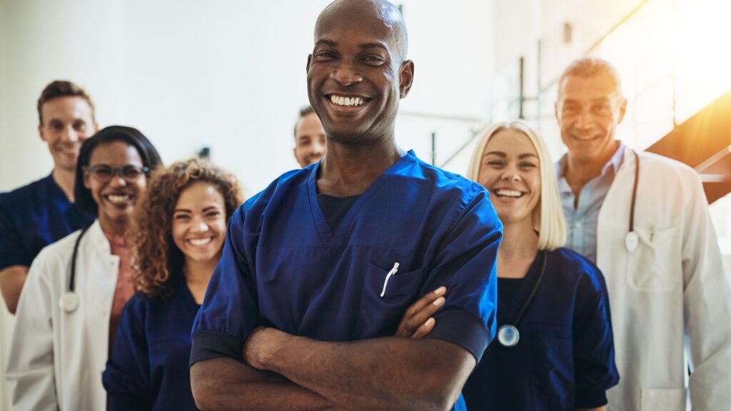 Médicos e médicas juntos e sorrindo em um hospital.